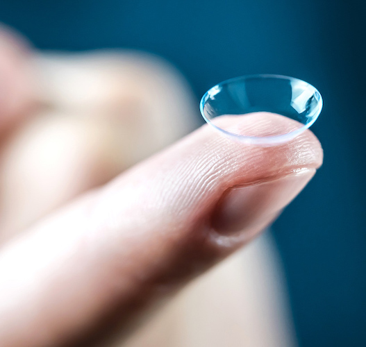 A finger holding a soft contact lens