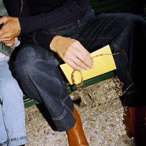 A pair of Izipizi blue tortoise reading glasses being held in a hand